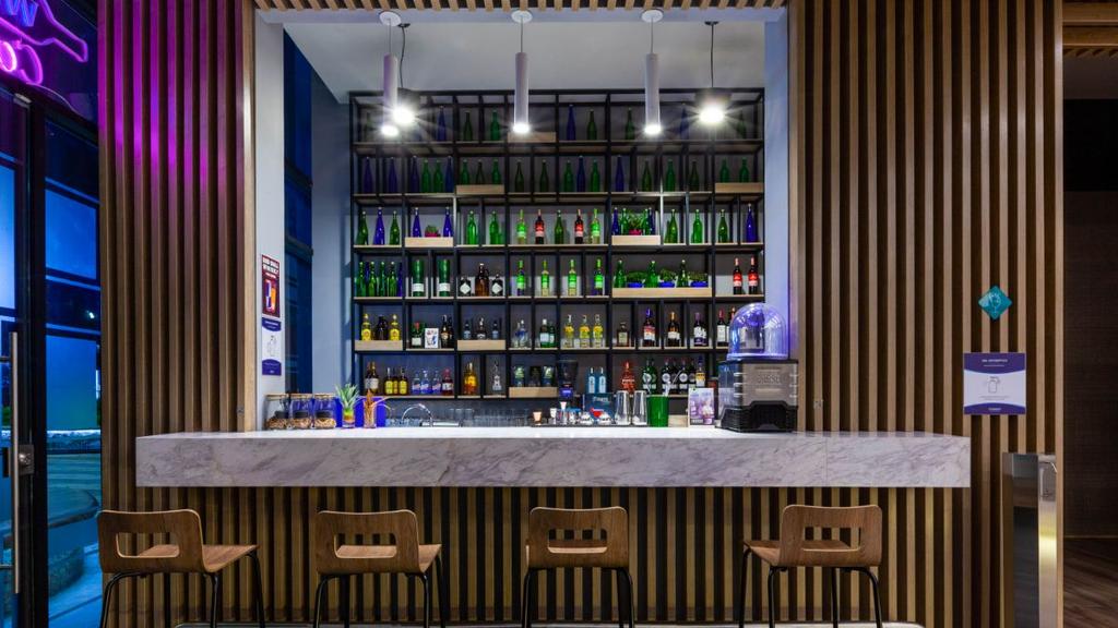 Barra con superficie de mármol, taburetes de madera y botellas organizadas