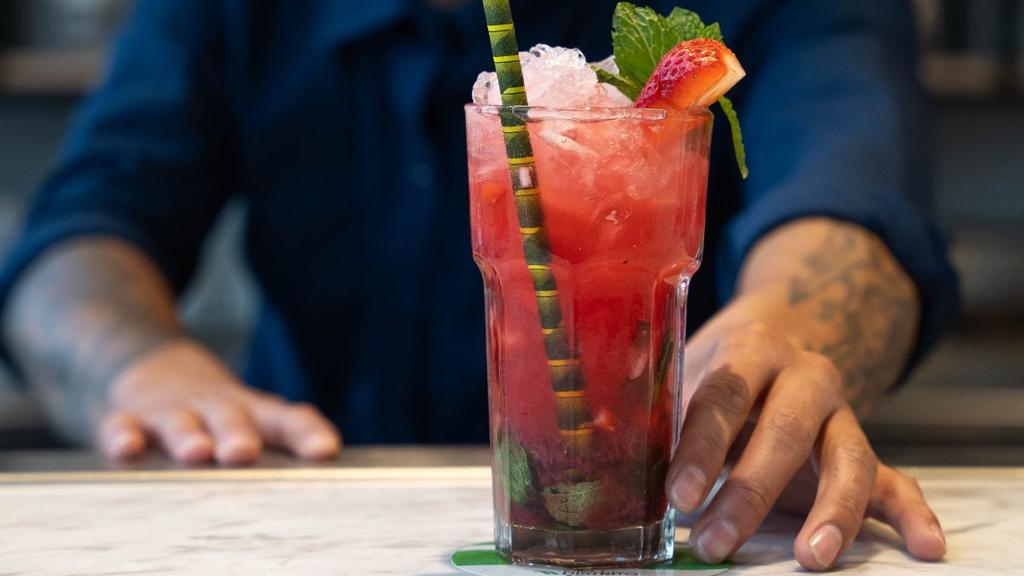 Bebida roja, hielo, menta y fresa en presentación llamativa