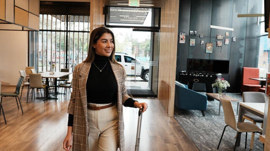 Persona con maleta saliendo de sala moderna con muebles y decoración elegante